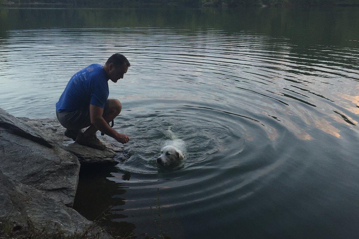 Sawyer swimming at the edge of Prettyboy Reservoir while Trey crouches on the rocks